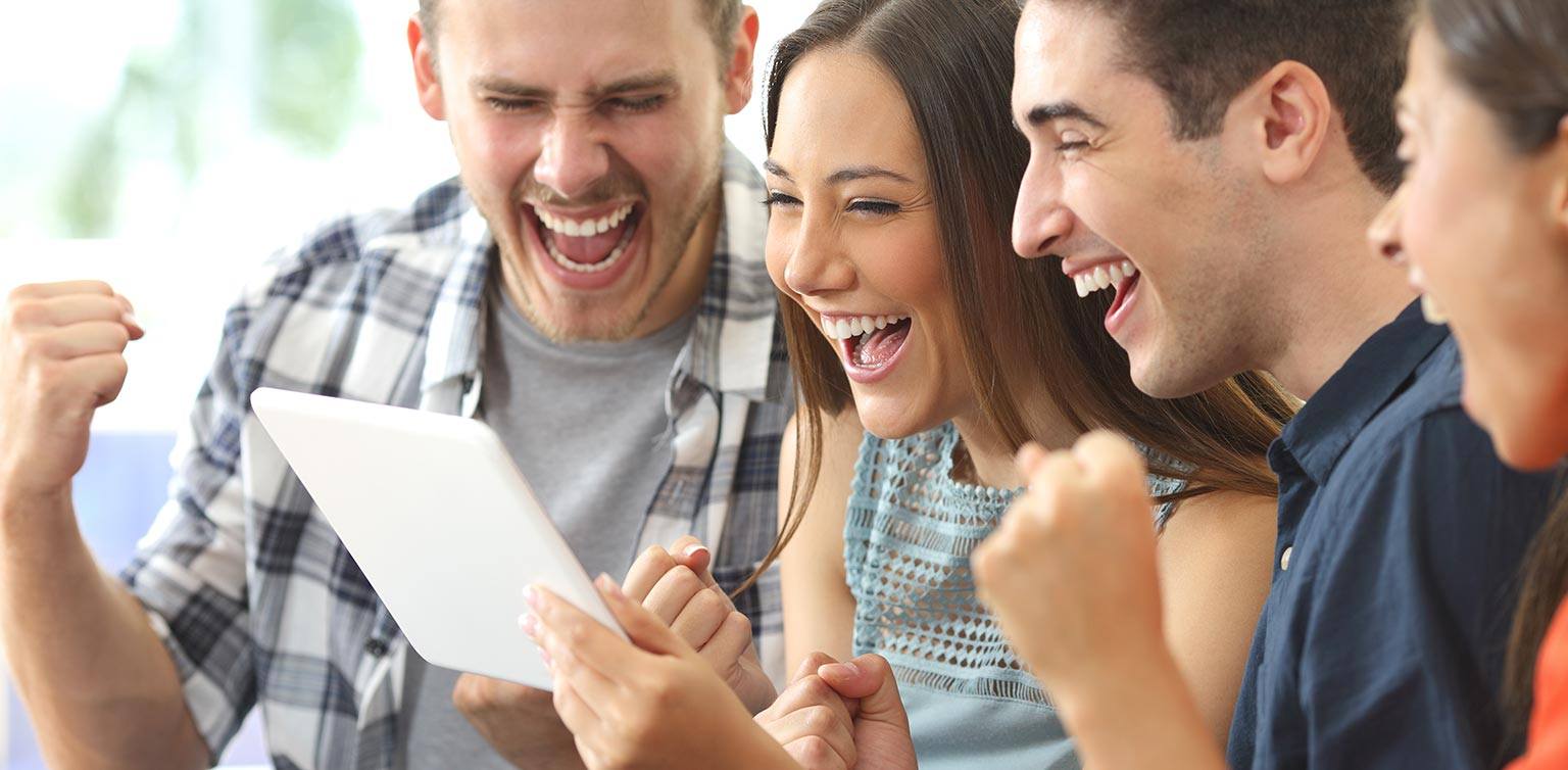 A photo of 4 super excitied people playing firey Red Stag Casino progressive jackpot slots on a mobile phone