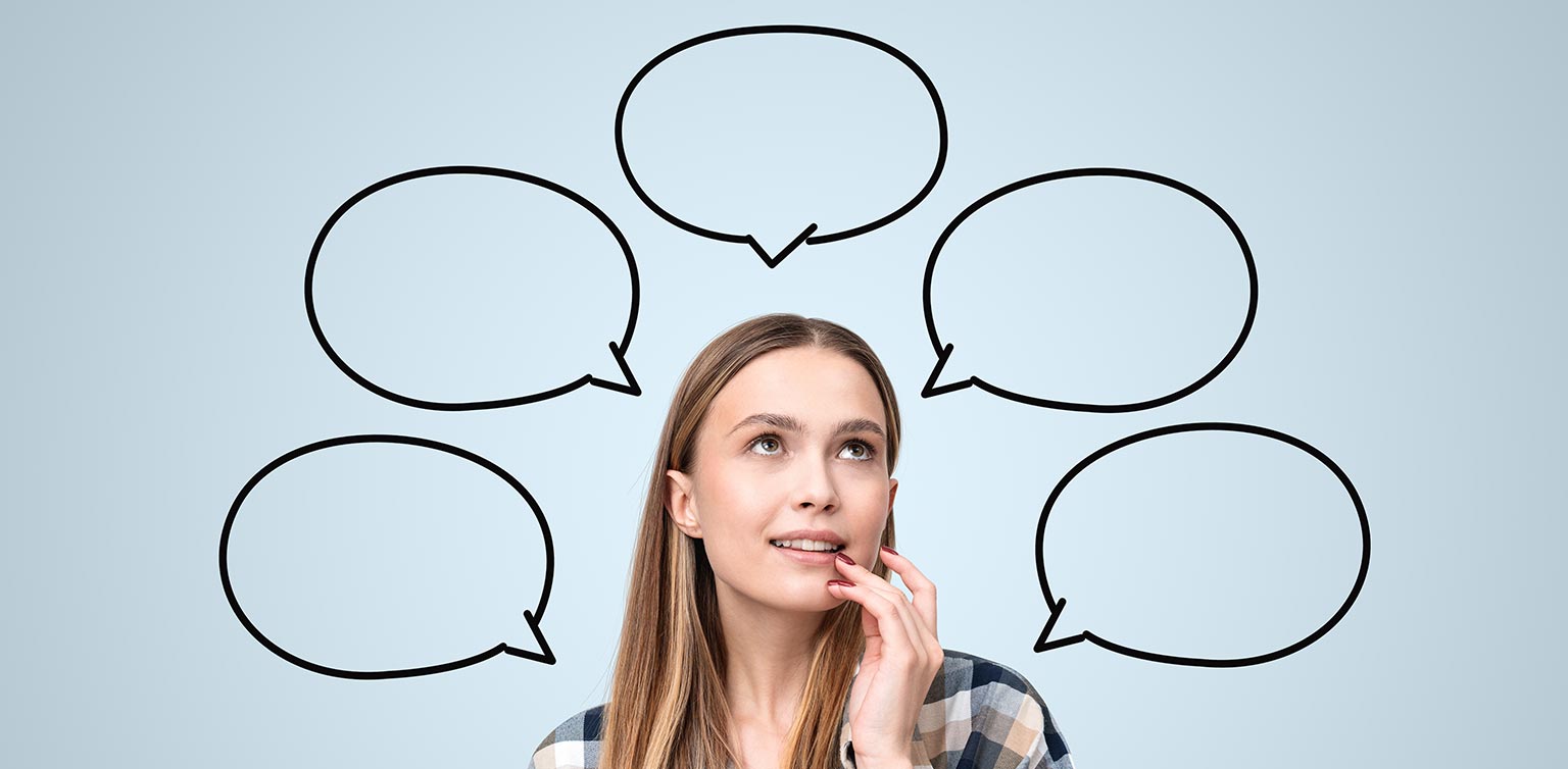 A photo of a woman with a thoughtful expression looking at empty speech bubbles around her head